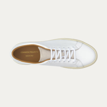 Top view of Common Projects Retro Low white leather sneaker, showcasing clean lacing and gold branding, available at SARTALE.