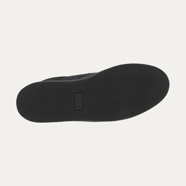 Outsole view of Common Projects 'Decades' black sneaker, showing herringbone tread pattern for grip and durability.