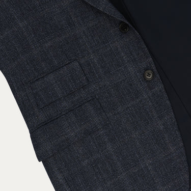 Close-up of Orazio Luciano suit jacket pocket detail in dark blue Prince of Wales wool, highlighting craftsmanship and premium fabric texture.