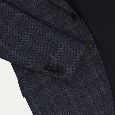Detailed view of Orazio Luciano suit sleeve with four-button cuff and Prince of Wales check pattern in dark blue wool, tailored for luxury appeal.