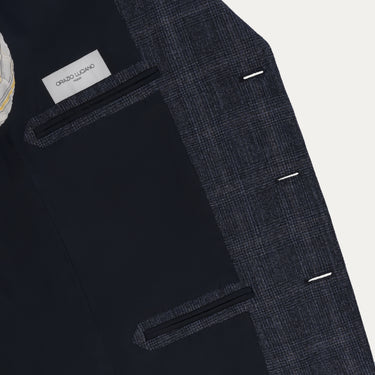 Interior of Orazio Luciano suit jacket in dark blue wool with Prince of Wales check, featuring branded label and inner pockets for elegant functionality.