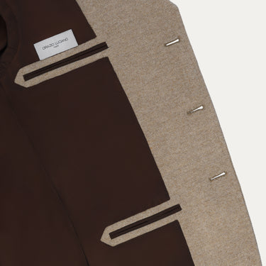 Interior view of Orazio Luciano beige wool jacket featuring brown lining and branded label, showcasing luxury finish and structure.