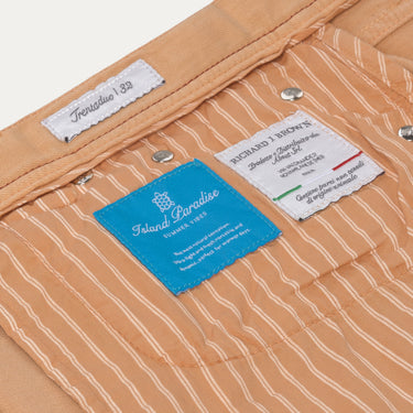 Interior label view of Richard J. Brown peach jeans with striped lining and brand tags, emphasizing luxury design and summer edition.