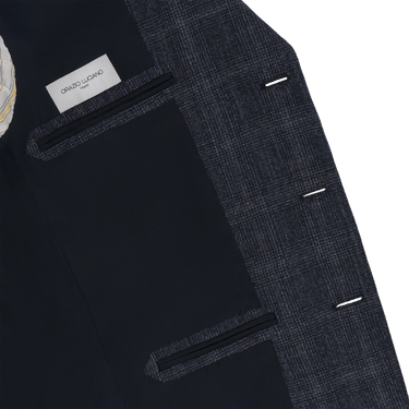 Interior of Orazio Luciano suit jacket in dark blue wool with Prince of Wales check, featuring branded label and inner pockets for elegant functionality.