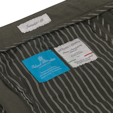 Interior label details of Richard J. Brown Caprera Trousers in Dark Green, highlighting Italian craftsmanship and Island Paradise SS25 collection.