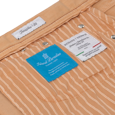 Interior label view of Richard J. Brown peach jeans with striped lining and brand tags, emphasizing luxury design and summer edition.